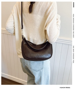 Detail of dark brown dumpling bag featuring pleated leather texture and metal buckle