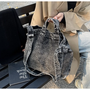 Detail of vintage washed denim tote bag with textured fabric and wide shoulder strap