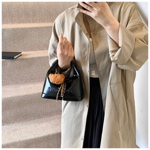 Glossy black handbag with letter embossing and cute brown bear pendant on display