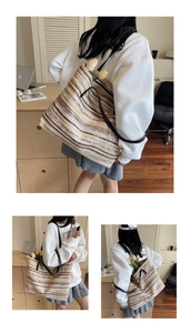 Detail of striped woven straw tote bag featuring long black leather shoulder straps