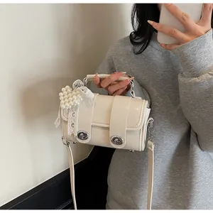 Dettaglio borsa in pelle bianco crema con ciondolo a cuore in perla e pizzo bianco