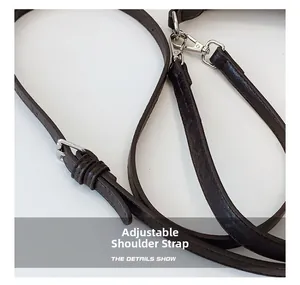 Detail of adjustable dark brown leather shoulder strap with silver metal buckle and clasp
