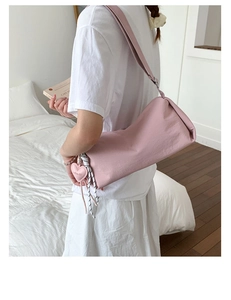 Sac bandoulière cylindrique en nylon rose avec pendentif cœur porté par un mannequin