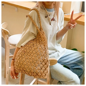 Detailed view of handmade hollow weave shoulder bag with inner pouch in a cafe setting