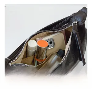 Detail view of inner capacity and pockets of the dark leather crossbody square bag