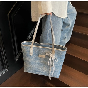 Detail of light blue glitter tote bag with lace pearl bow charm on wooden stairs