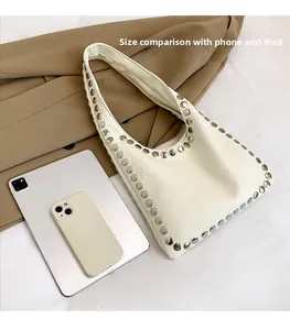 White PU leather hobo bag with silver studs, showing size comparison with phone and iPad