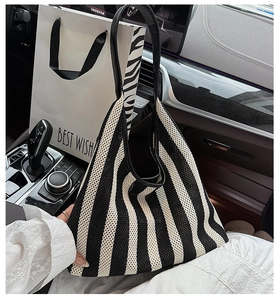 Close-up of black and white striped knit tote bag with leather handles on a car seat