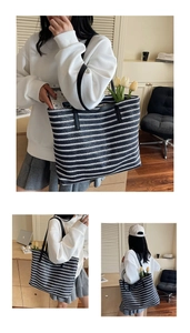 Detail of a large woven tote bag with black and white stripes and leather straps