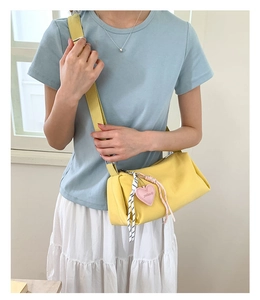 Detail of a lemon yellow nylon crossbody bag with cute heart charm and adjustable strap