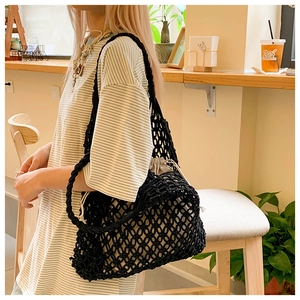 Detail of black hollow woven tote bag with beige drawstring pouch liner in cafe setting