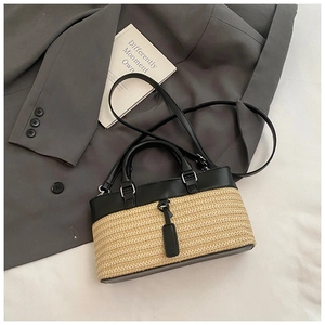 Detail of straw woven and black leather stitching with silver metal buckle on a tote bag