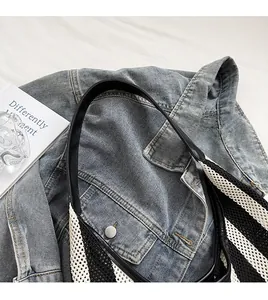 Close-up of black and white striped knit tote bag with leather strap on denim jacket