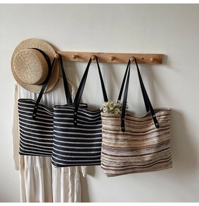 Detailed close-up of woven striped tote bag texture with premium leather shoulder straps
