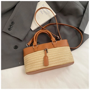 Detail of woven straw handbag with brown leather trim resting on a grey blazer suit