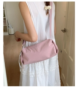 Detailed view of pink pleated nylon shoulder bag with a striped cord pendant accessory