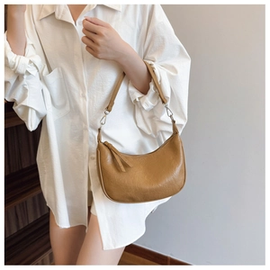 Detail view of camel crescent bag with smooth zipper closure and long leather tassel