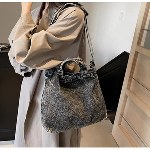 Detail of washed denim tote bag showing adjustable strap and vintage texture