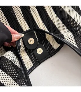 Detail of nautical striped tote bag showing black leather trim and gold magnetic snap closure