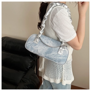 Dettaglio borsa baguette in denim lavaggio chiaro con tracolla argento arricciata