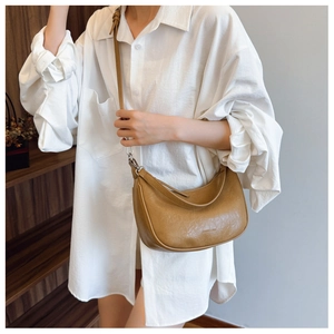 Close-up of khaki half-moon leather bag showing micro-wrinkle texture and brand detail