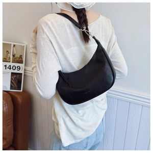 Detail of black crescent shoulder bag featuring textured leather and silver hardware