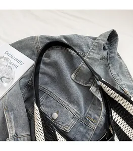 Detail of nautical striped tote bag with black faux leather strap on denim jacket