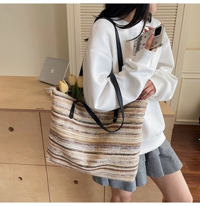 Model wearing a large striped straw tote bag with black handles and tulip decorations