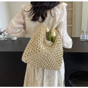 Détail du motif au crochet ajouré et texture beige sur le grand sac cabas d'été tressé