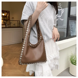 Detail of coffee brown leather tote bag featuring stylish silver metal rivet decorations