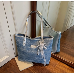 Detail of denim texture tote bag with silver leather handles and pearl bow charm