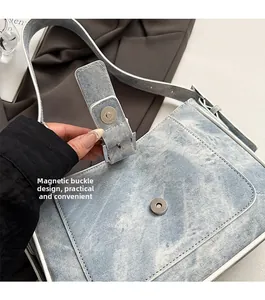 Detail of the magnetic buckle on a light blue denim crescent shoulder bag for women