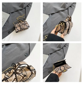 Detail of snakeskin texture on a mini crossbody bag with gold chain and top handle