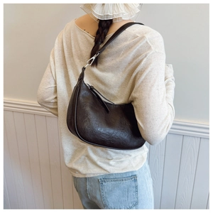Detail of a black crescent shoulder bag with vintage crinkle texture and silver buckle