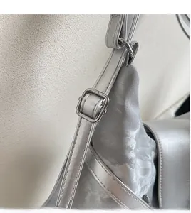 Detailansicht des verstellbaren Riemens und des silbernen Metallic-Stoffs der Tasche
