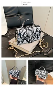 Dettaglio della borsa in pelle PU nera con texture a serpente e catena dorata