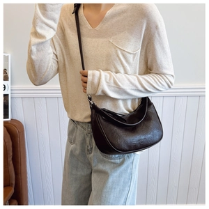 Detail of dark brown leather crescent bag showing vintage pleated texture and silver hardware