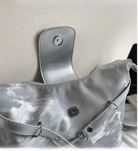 Details einer silbernen Metallic-Tasche mit Magnetverschluss und polierten Beschlägen