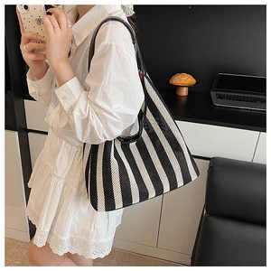 Close-up of nautical striped tote bag with woven texture and black leather shoulder strap