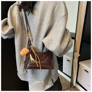 Close-up of deep brown glossy leather handbag with Yimeiya logo and plush bear charm