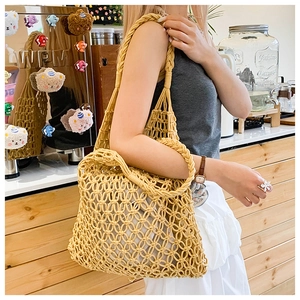 Close-up of hollow woven straw tote bag with drawstring inner pouch and wide shoulder strap