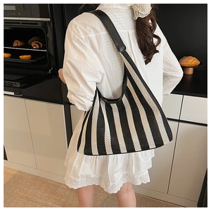 Close-up of black and white striped woven hobo bag with a premium black leather strap