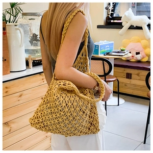 Detail of a mustard yellow woven hollow mesh tote bag with chunky shoulder straps