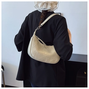 Detail of beige half-moon hobo bag featuring premium pleated leather texture and sleek zipper