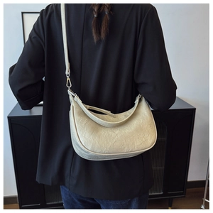 Macro detail of beige crescent bag with wrinkled leather texture and embossed logo