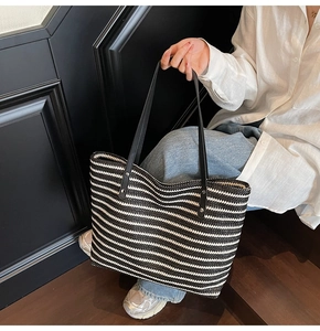 Detail of hand-woven striped tote bag showing durable leather straps and woven texture