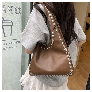 Detail view of brown vintage underarm bag featuring large silver metal rivets and leather texture