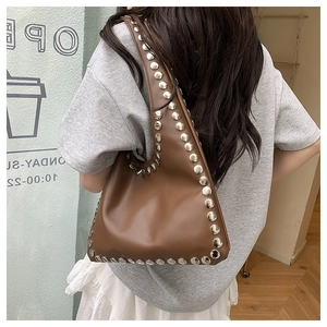 Détail d'un sac à bandoulière marron orné de gros rivets argentés au style bohème