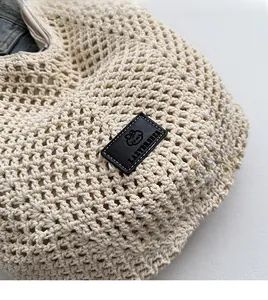 Detailed close-up of handmade cream woven mesh tote bag with a black leather logo patch