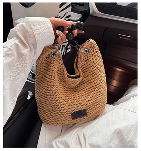 Detail of crochet bucket bag with thick khaki knit texture and black bead chain handle